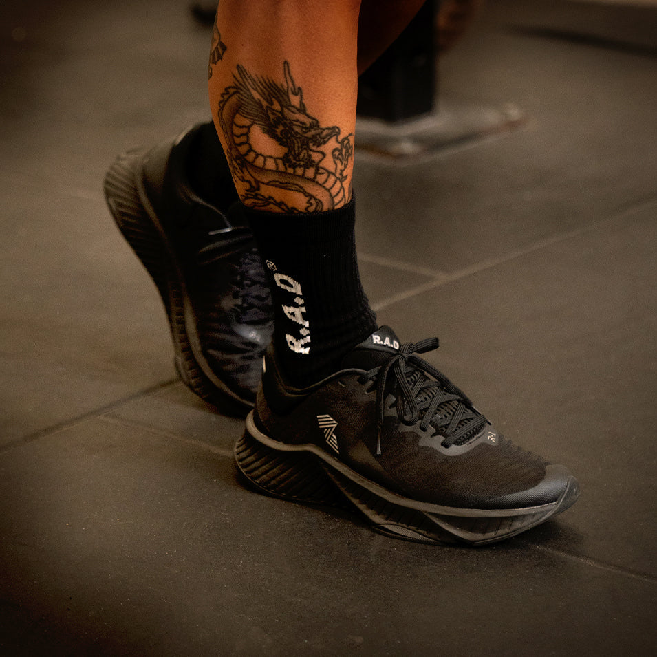 Black running shoes with dragon tattoo.